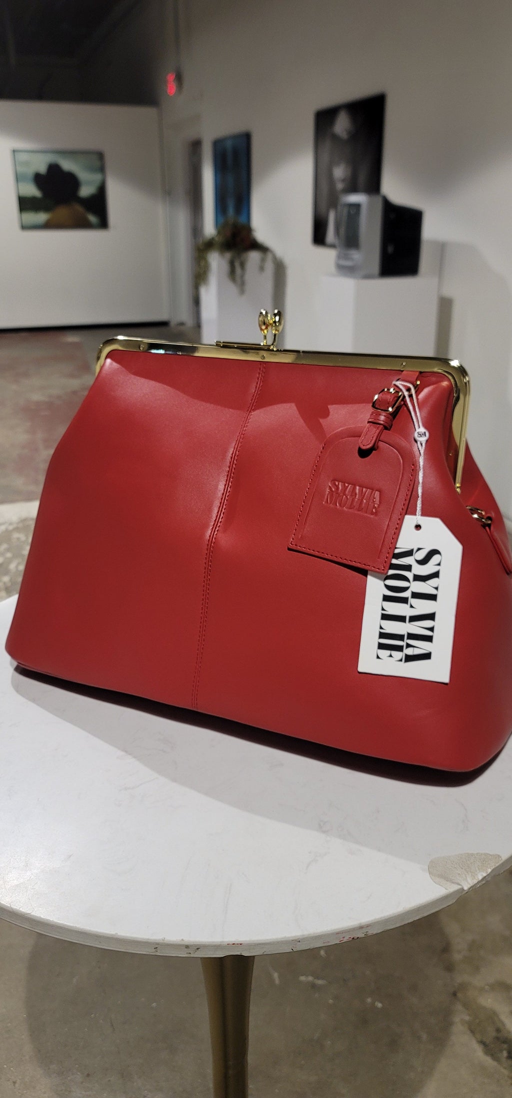 Red leather kiss-lock handbag with an embossed Sylvia Mollie hangtag