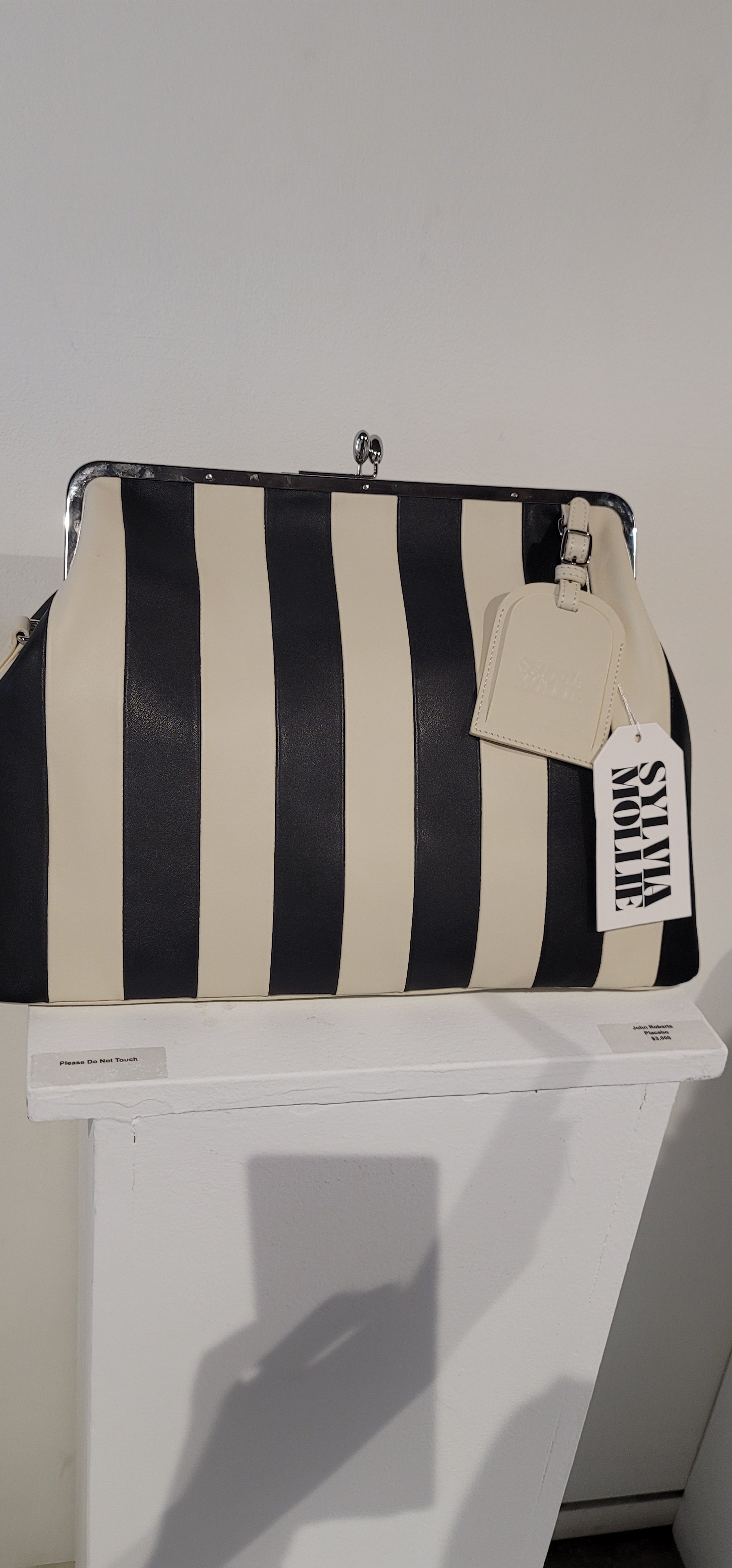 The Fannie Bag in ecru and black stripe with a silver frame and leather hangtag