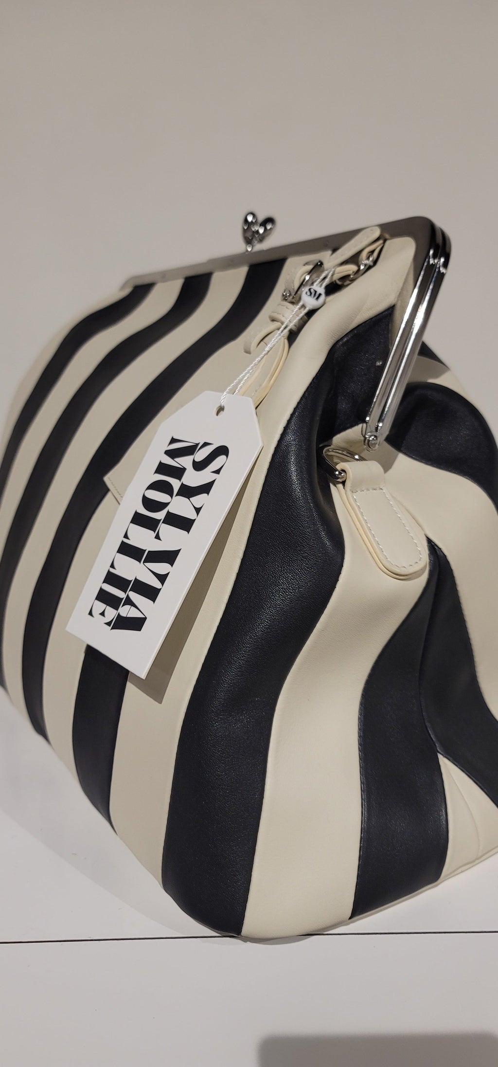 The Fannie Bag in ecru and black stripe displayed on a white plinth