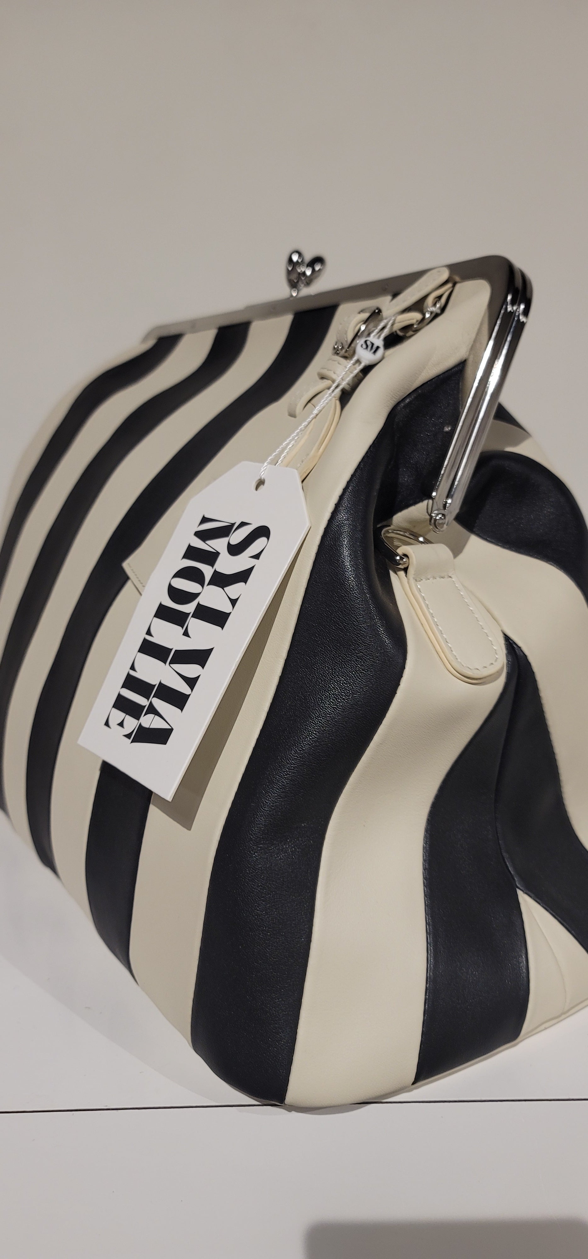 The Fannie Bag in ecru and black stripe displayed on a white plinth