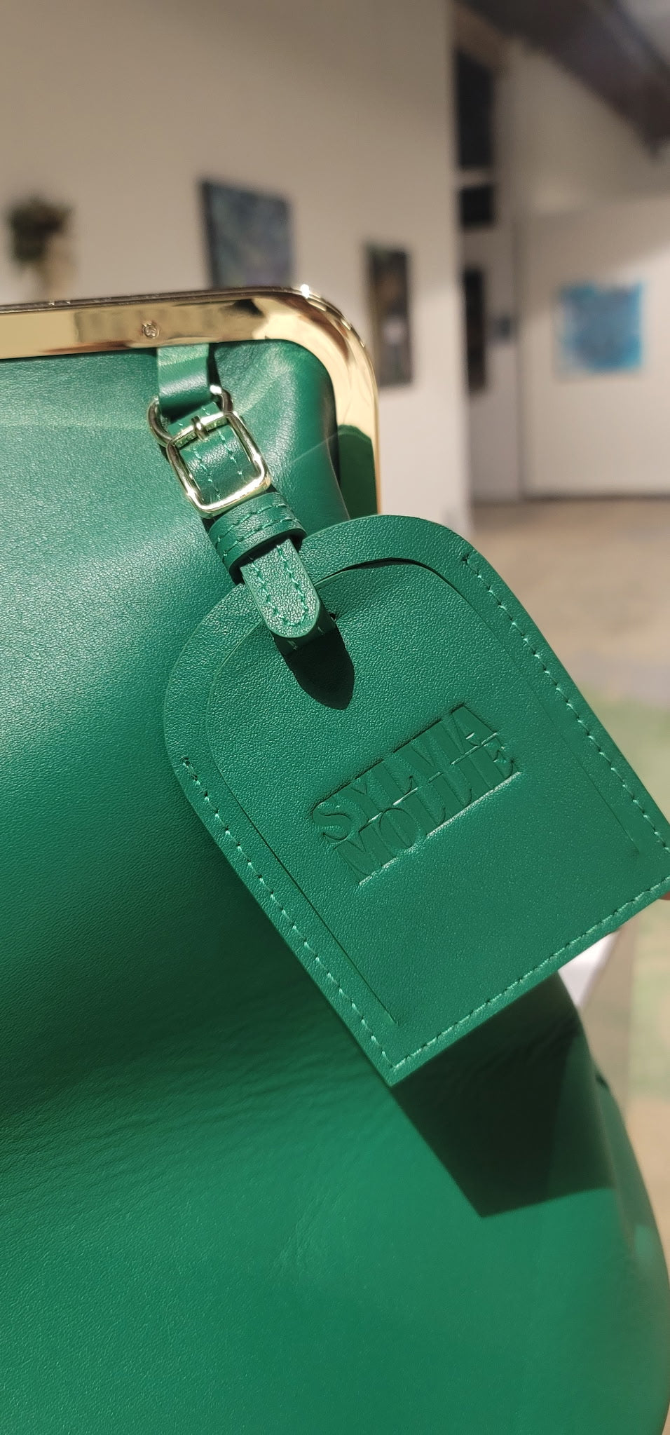 Green leather kiss-lock handbag with an embossed Sylvia Mollie hangtag