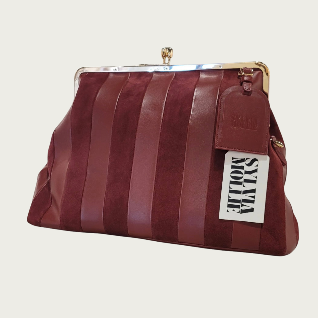The Fannie Bag in burgundy with alternating leather and suede vertical panels and a kiss-lock frame