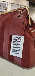 Brown handbag with a visible brand tag on a light background