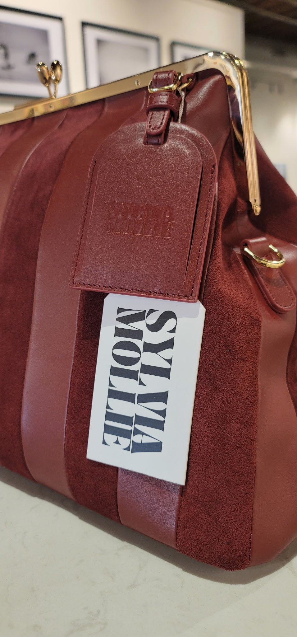 Burgundy leather and suede striped handbag with a gold-tone frame and embossed hangtag