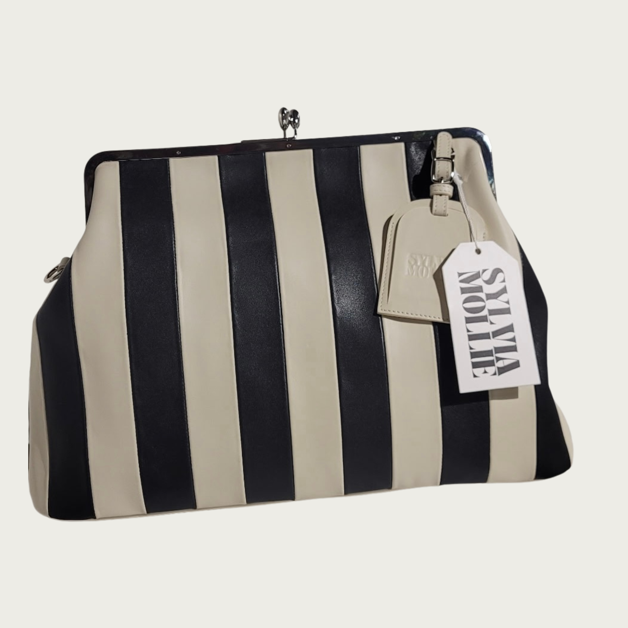 The Fannie Bag in ecru and black striped leather with a silver kiss-lock frame and embossed hangtag