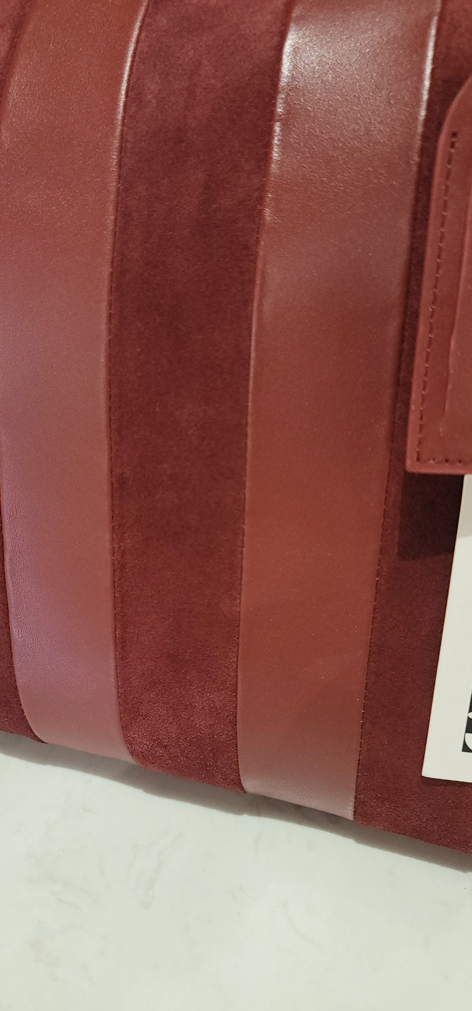 Close-up of the burgundy leather and suede panels and embossed logo tab