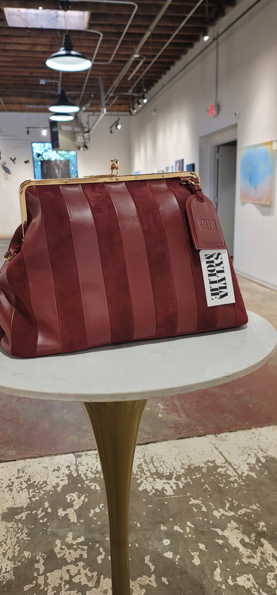 Red striped bag with a visible brand label on a white table in an indoor setting.